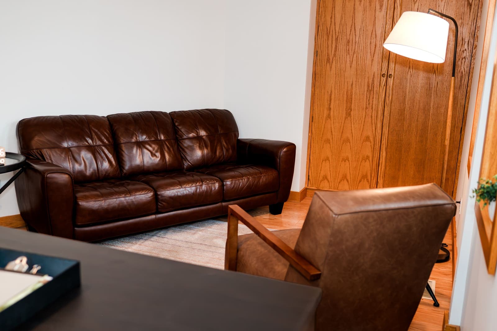 Therapy room with a brown leather couch and armchair