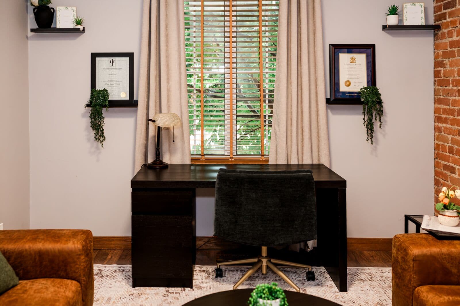 Therapy office with a desk, exposed brick wall, and leather seating