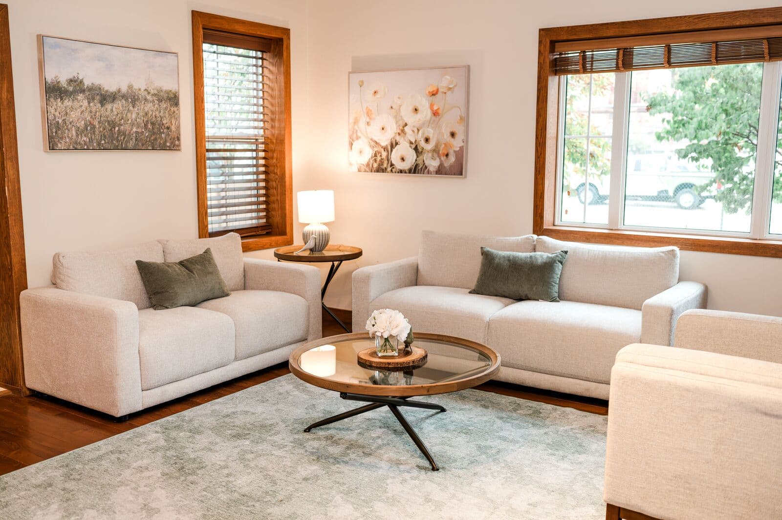 Waiting room with two cream loveseats, soft lighting, and botanical artwork
